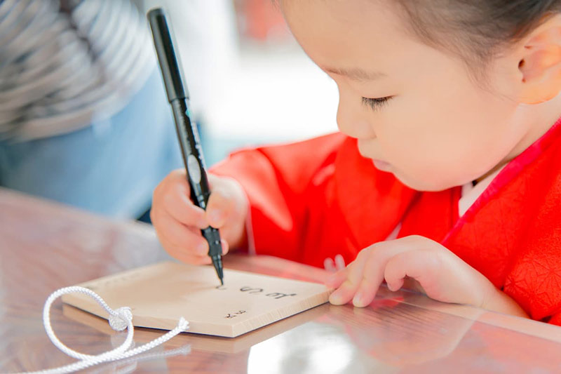 絵馬に願いを書く子供